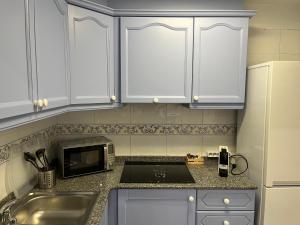 uma cozinha com armários brancos, um lavatório e um micro-ondas em Bet&CoBeach Apartments em Valência
