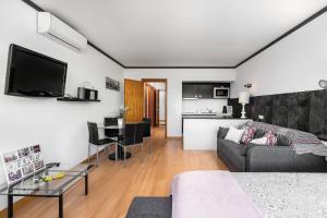 a living room with a gray couch and a kitchen at Apartamento Portugal in Quarteira