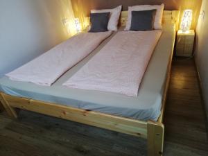een houten bed met twee kussens erop bij Liberty Apartman Bükfürdő in Bük