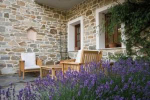 uma casa de pedra com duas cadeiras e flores roxas em Villa Kastanodasos em Emporio