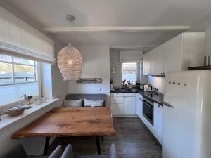 a kitchen with a wooden table and a white refrigerator at To Huus - im Süden von Westerland in Westerland