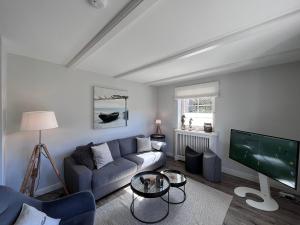 a living room with a blue couch and a tv at To Huus - im Süden von Westerland in Westerland (Sylt)