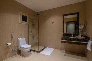 a bathroom with a toilet and a sink and a mirror at Enala Hotel - Tabuk in Tabuk