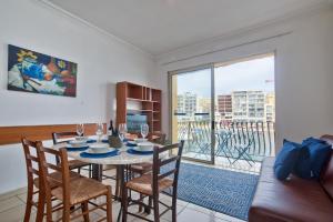 a dining room with a table and chairs and a large window at Morina Court - St Julians Seaside Bliss Apartments and Penthouse by ShortletsMalta in St. Julianʼs