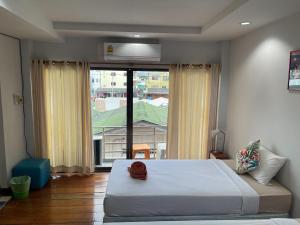 een slaapkamer met een groot bed en een groot raam bij Jenny Hostel HuaHin in Hua Hin