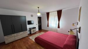 a bedroom with a red bed and a television at Pensiunea Miruna Slănic Moldova in Slănic-Moldova