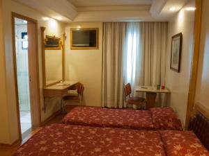 um quarto de hotel com uma cama, uma secretária e uma janela em King Hotel em São Paulo