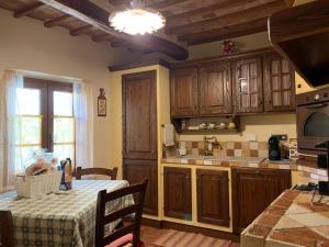 a kitchen with wooden cabinets and a table with a tablecloth at La Casa degli Archi in Montepulciano