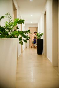 a man and a child walking down a hallway with plants at Hotel Cicò in Torre Santa Sabina