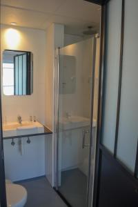 a bathroom with a shower and two sinks and a toilet at Hotel Sandeshoved Zeedijk in Nieuwpoort