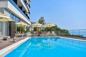 a swimming pool with chairs and umbrellas on a building at Katamare Hotel in Budva