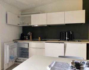 una cucina con armadi bianchi e piano di lavoro bianco di LuGa Apartments a Campomarino