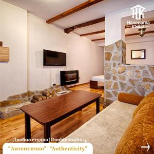 a living room with a table and a stone wall at Guest House Nachevata Kashta in Veliko Tŭrnovo