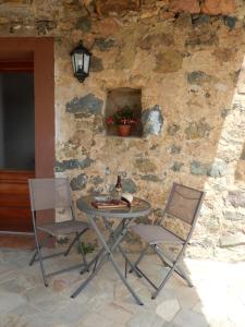 a table and two chairs in front of a stone wall at Maison de village située dans le magnifique Golfe de Porto in Osani