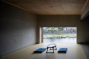 ein Zimmer mit einem Tisch und zwei Matten vor einem Fenster in der Unterkunft Kamohan in Kyoto