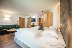 ein Hotelzimmer mit einem Bett mit weißen Kissen in der Unterkunft Vitaurina Royal Hotel in Mühlen in Taufers