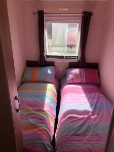two beds in a small room with a window at 10 berth caravan on marine park in Rhyl in Rhyl