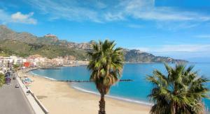 two palm trees on a beach near the water at AG Luxury Rooms in Giardini Naxos