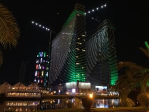 a large building with green lights on it at night at Luxury Studio with Ocean View in Batumi