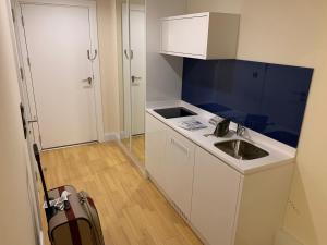 a small white kitchen with a sink and a door at Luxury Studio with Ocean View in Batumi