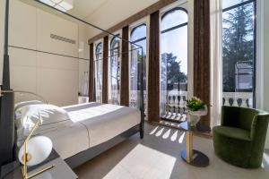 Schlafzimmer mit einem Bett, einem Stuhl und Fenstern in der Unterkunft Hotel Villa Soligo - Small Luxury Hotels of the World in Farra di Soligo