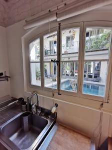 eine Küche mit Spüle und zwei Fenstern in der Unterkunft La villa Marseillanaise in Marseillan