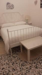 - une chambre dotée d'un lit blanc avec un banc et une table dans l'établissement B&B La Maddalena, à Sammichele di Bari