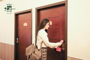 a woman is standing in front of two doors at Anho Chew Hotel in Luodong