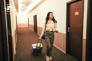 a woman walking down a hallway with a suitcase at Anho Chew Hotel in Luodong