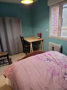a bedroom with a bed and a table and a window at la grange in Coigneux