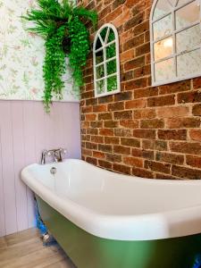 a white bath tub sitting next to a brick wall at The Townhouse 101 in Sandown