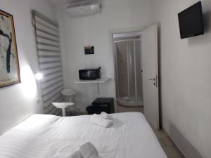um quarto com uma cama branca e uma televisão em Guest House San Pietro em Roma