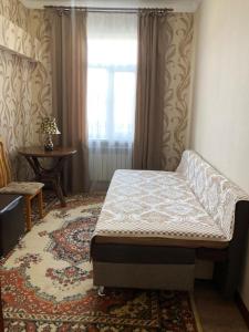 a bedroom with a bed and a window and a rug at Hostel Viator in Almaty