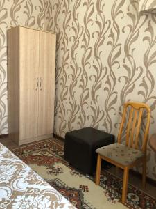 una camera da letto con sedia, valigia e armadietto di Hostel Viator a Almaty