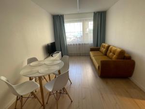 uma sala de estar com um sofá, uma mesa e cadeiras em Livinga Lovely 1-bedroom apartment em Mažeikiai