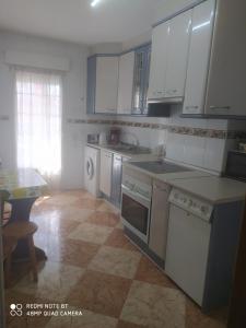 a kitchen with white appliances and a table and a table at Vivienda céntrica en Las Navas in Las Navas del Marqués