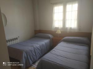 two beds in a room with two windows at Vivienda céntrica en Las Navas in Las Navas del Marqués