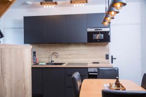 une cuisine avec des armoires noires et une table en bois dans l'établissement Gîtes de La Vesée, à La Chapelle dʼArmentières