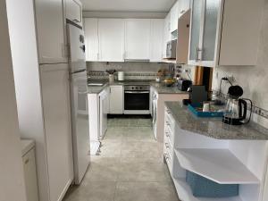 a kitchen with white appliances and white cabinets at Casa das Cores in Sesimbra