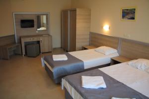 a hotel room with two beds and a television at Александра Палас in Kranevo