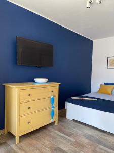 a bedroom with a bed and a tv on a blue wall at Morza Szum in Dziwnów