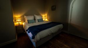 a bedroom with a large bed with two lights on it at B&B Maison Rabelais in De Haan