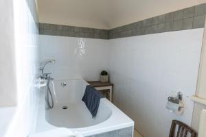 W białej łazience znajduje się umywalka i lustro. w obiekcie B&B Maison Rabelais w mieście De Haan