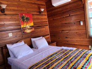 1 dormitorio con 1 cama en una pared de madera en Blue Wave Guest House en Caye Caulker