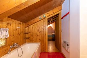 a bathroom with a tub and wooden walls at Dimora Catitti in Mazzin