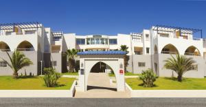 a large white building with palm trees in front of it at Village Naturiste NATUREVA & SPA - Babylone NATURISME in Cap d'Agde
