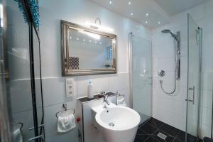 a bathroom with a sink and a shower and a mirror at Freundliche Ferienwohnung (Souterrain) mit Gartenmitbenutzung im Haus Lotus in Bad Urach