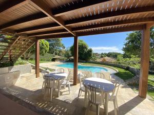 a patio with tables and chairs and a swimming pool at Linda Casa Buzios in Búzios