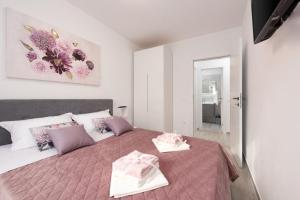 una camera da letto con un grande letto con cuscini rosa e viola di Marin a Čižići