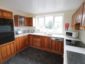 a kitchen with wooden cabinets and a large window at Ty Rhos, Farm Stay, sleeps 4, Rhoshirwaun 2 miles from Aberdaron in Aberdaron